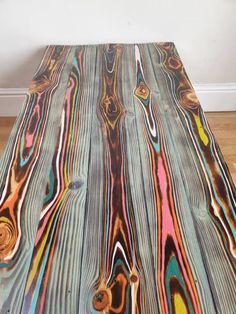 a table made out of wood with multicolored paint on it's surface