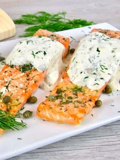 the salmon is covered in white sauce and garnished with green olives