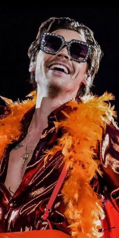 a man with sunglasses on his face and an orange feather around his neck that says love on tour ts's almost part 1