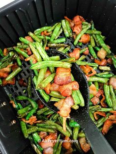 asparagus and bacon stir fry in a black skillet with tongs on the side