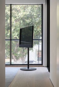 a flat screen tv sitting on top of a metal stand in front of a window