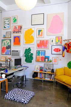 a room filled with lots of colorful art on the wall and furniture in front of it