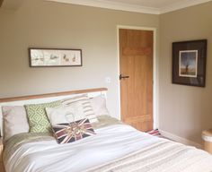 a bed sitting in a bedroom next to a wooden door and framed pictures on the wall