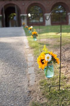 sunflowers and daisies in vases are hanging on the side of the road