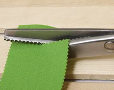 a pair of scissors with a green piece of paper on it