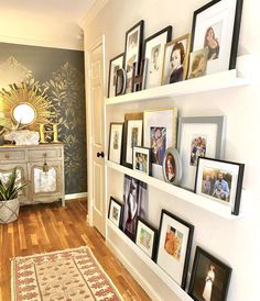 a wall with many pictures on it and a rug in front of the door way