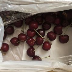 a bag full of cherries sitting on top of a table next to a fork