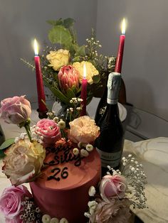 a birthday cake with candles and flowers on it, next to a bottle of wine