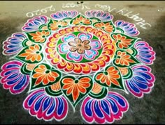 colorful rangdi design on the ground with words written in white writing and an orange flower