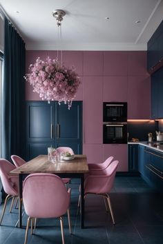 a dining room table with pink chairs and blue cabinets in the background, next to a window