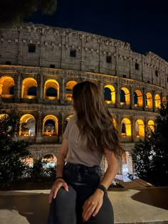 a woman sitting in front of the colossion at night