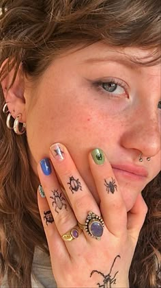 a woman with tattoos on her hands and fingers, holding her hand to her face