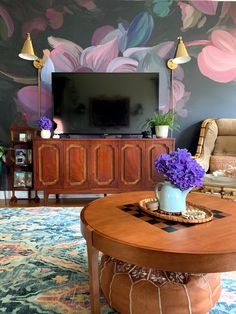 a living room with flowers on the table and a large tv in the back ground