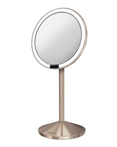 a round mirror sitting on top of a metal stand in front of a white background