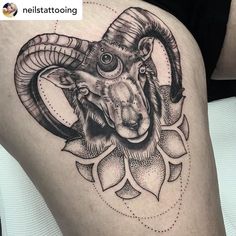 a ram tattoo on the back of a woman's thigh, with flowers around it