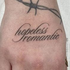 a hand with barbed wire and the word hopeless romantic written on it's palm