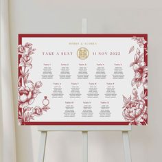 a wedding seating chart on a easel with flowers and leaves in red, white and gold