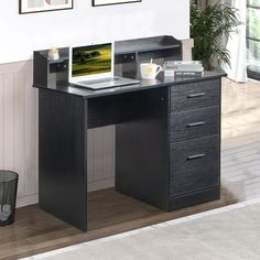 a computer desk with a laptop on top of it in front of a white wall