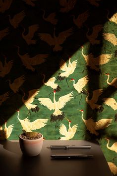 a desk with a pen and some birds on it next to a wallpapered background