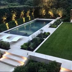 an outdoor pool surrounded by greenery and lights in the middle of a garden with steps leading up to it