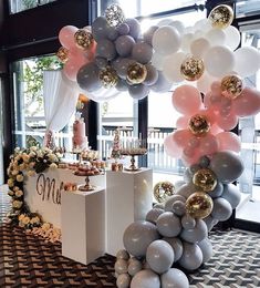 a table topped with balloons and cake next to a window