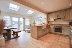 an open kitchen and dining area with wooden floors, white walls and skylight windows