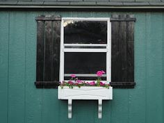 a window box with flowers in it on the side of a green building