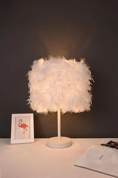 a lamp that is on top of a table next to a book and some pictures