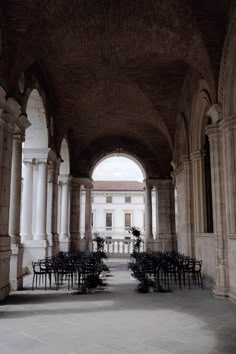 there are many tables and chairs in the room with arches on either side of them