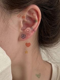 a woman with tattoos on her ear and behind the ear is a small flower, heart, pineapple