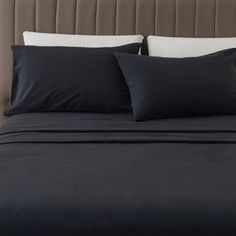 a bed with black sheets and pillows on it