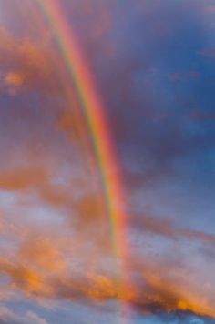 a double rainbow in the sky with clouds