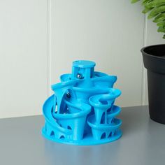 a blue plastic object sitting on top of a table next to a potted plant