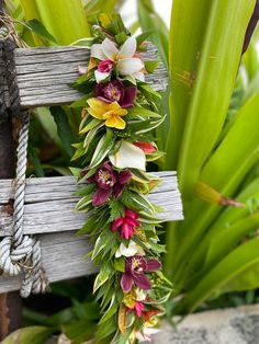 a cross decorated with flowers and leaves on the side of a wooden bench in front of palm trees