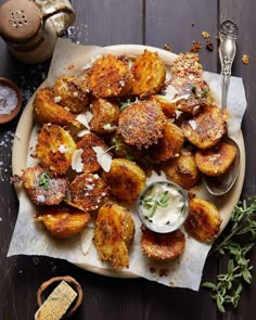 some fried potatoes on a plate with ranch dressing and herbs next to the side dish