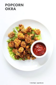 a white plate topped with lettuce covered in toppings next to a bowl of ketchup