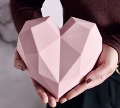 a woman holding a pink origami heart shaped box in her hands with the lid open