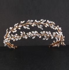 a gold and white tiara with crystal leaves on the headpiece is shown against a black background