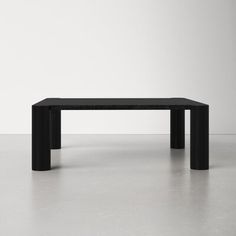 a black table sitting on top of a floor next to a white wall in an empty room