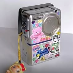 an old fashioned camera with stickers on it and a keychain attached to it