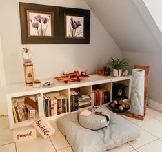 a room with bookshelves, pillows and pictures on the wall above them is shown