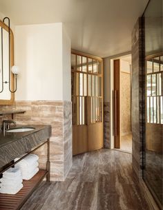 a bathroom with marble counter tops and wooden floors, along with large mirrors on the wall