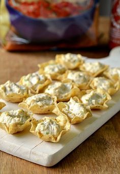 small appetizers are sitting on a cutting board next to a bag of chips