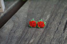 two small red and green beads sitting on top of a wooden table next to each other