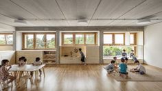 children are sitting at desks in the middle of a room with wood flooring