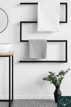 a bathroom with black shelves and white towels on the wall, along with a plant