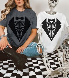 This Skeleton Costume Tee features a stylish twist with a skeleton rib cage design layered beneath the image of a sleek suit. Perfect for those who want to add a spooky, yet classy, flair to their outfit, the shirt displays a detailed rib cage with bones popping out from underneath a sharp suit jacket and tie. Whether you're dressing up for Halloween or just want to showcase your quirky style, this shirt offers a fun and unique way to combine spooky skeleton vibes with formal attire. Ideal for c Rib Cage Shirt, Skeleton Suit, Skeleton Rib Cage, Skeleton Top, Skeleton Tshirt, Shirt Display, Skeleton Costume, Suit Shirt, Suit Shirts