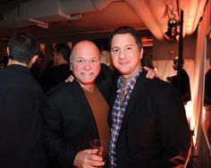 two men standing next to each other at a party