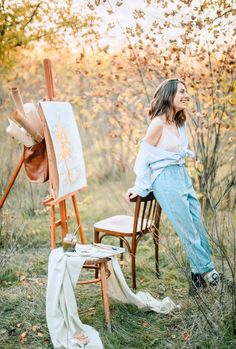 a woman sitting on a chair next to an easel