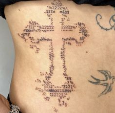 the back of a woman's stomach with an intricate cross and numbers on it